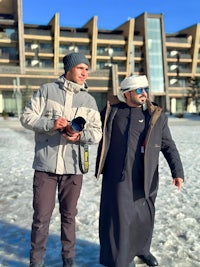 two men standing in front of a building in the snow