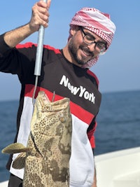 a man holding a fish on a boat