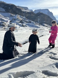 a man and two children playing in the snow