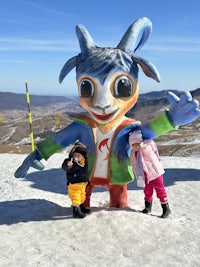 two children posing in front of a giant goat