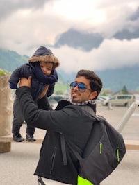 a man holding a baby in front of mountains