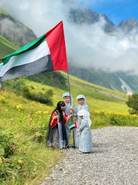 a group of children holding a uae flag in the mountains