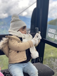 a child sitting on a cable car taking a picture