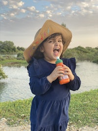 a little girl with a hat and a bottle of water