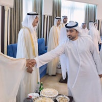 a man in a white robe shaking hands with a man in a white robe