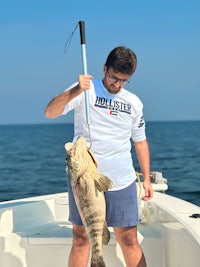 a man holding a large fish on a boat